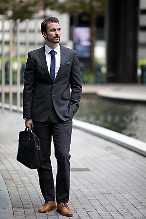A young man wearing a suit is standing in a business quarter.
