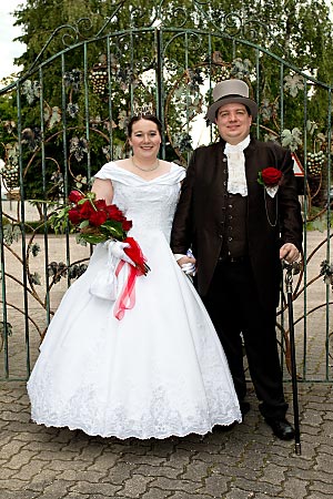 A bridal couple is standing in front of a gate.